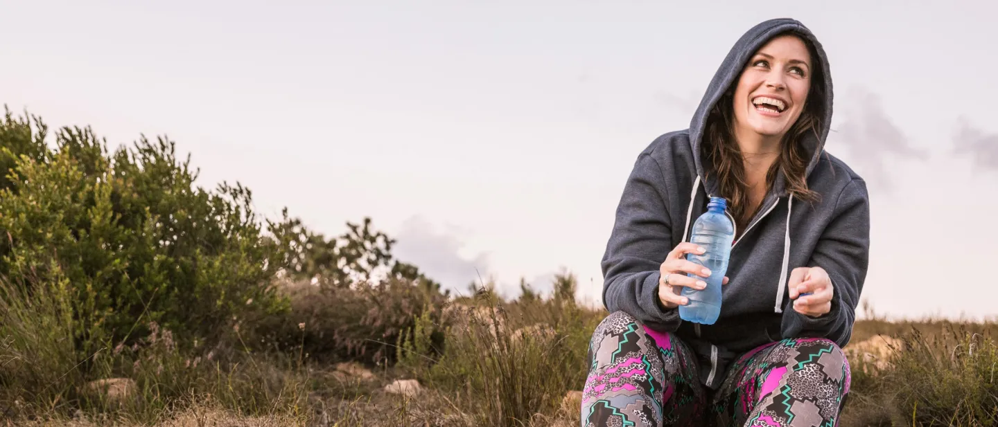Woman in a hooded jacket, holding a plastic water bottle