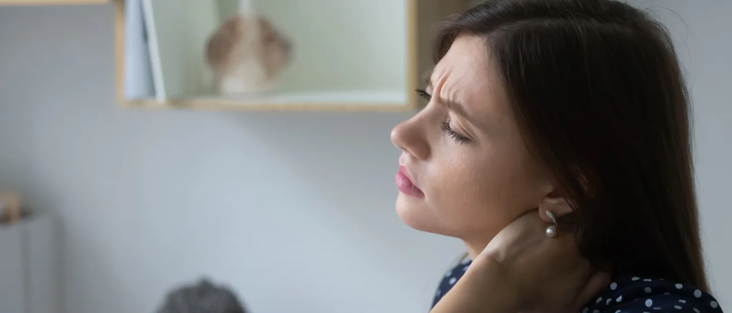 Woman holding her neck with a pained look on her face