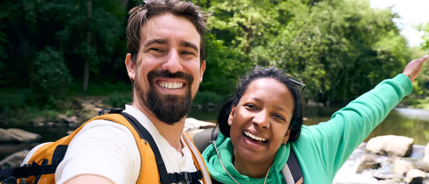Man and woman smiling by a creek