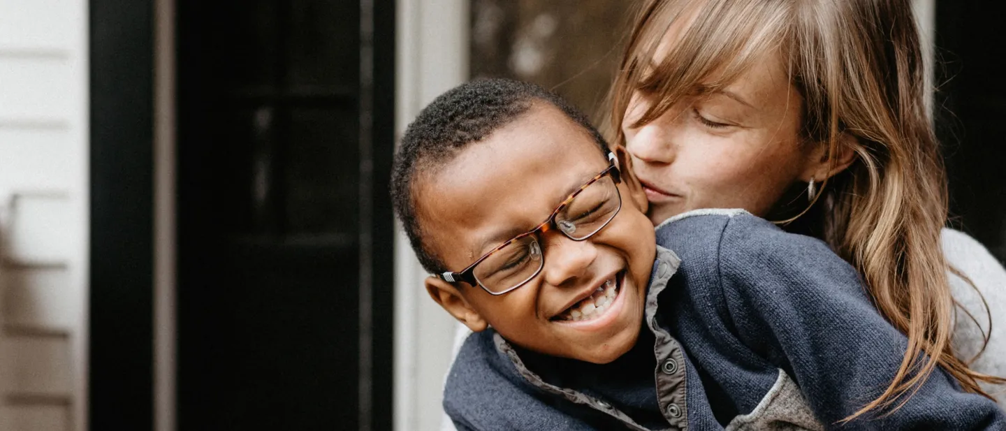 A woman holding a boy, wearing glasses