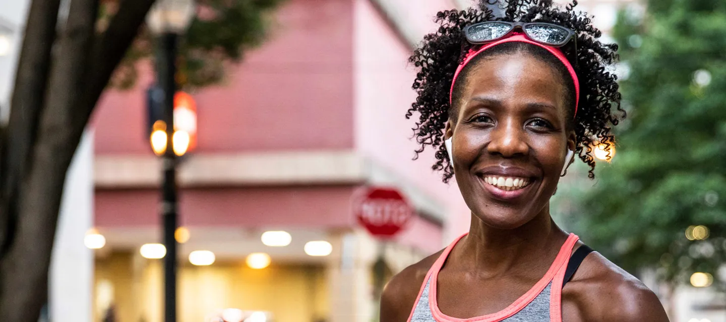 Woman smiling with sunglasses on her head and wearing a tank top