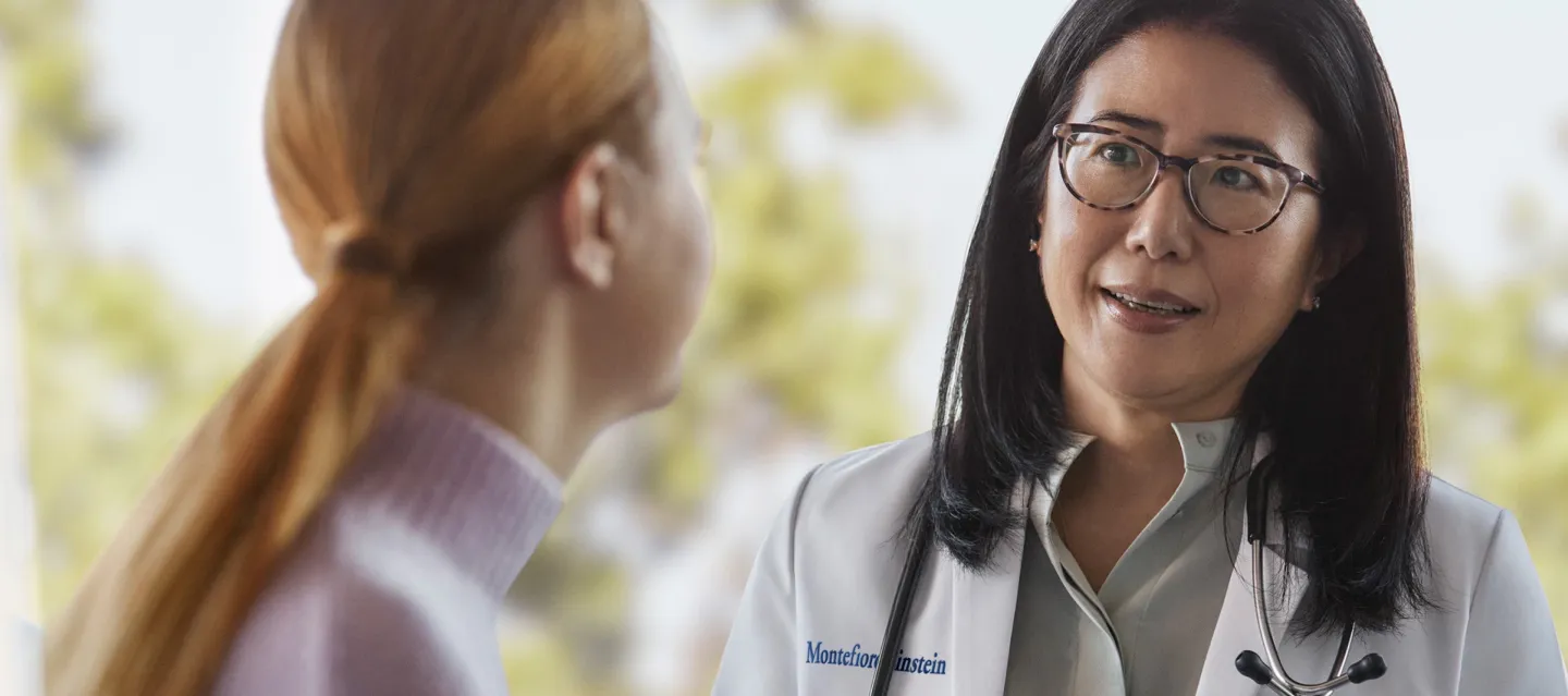 Provider in lab coat speaking with woman 