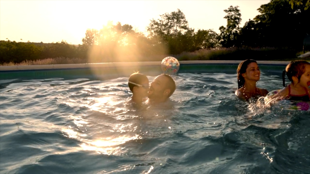 Friends and family on sunny afternoon playing in a backyard pool