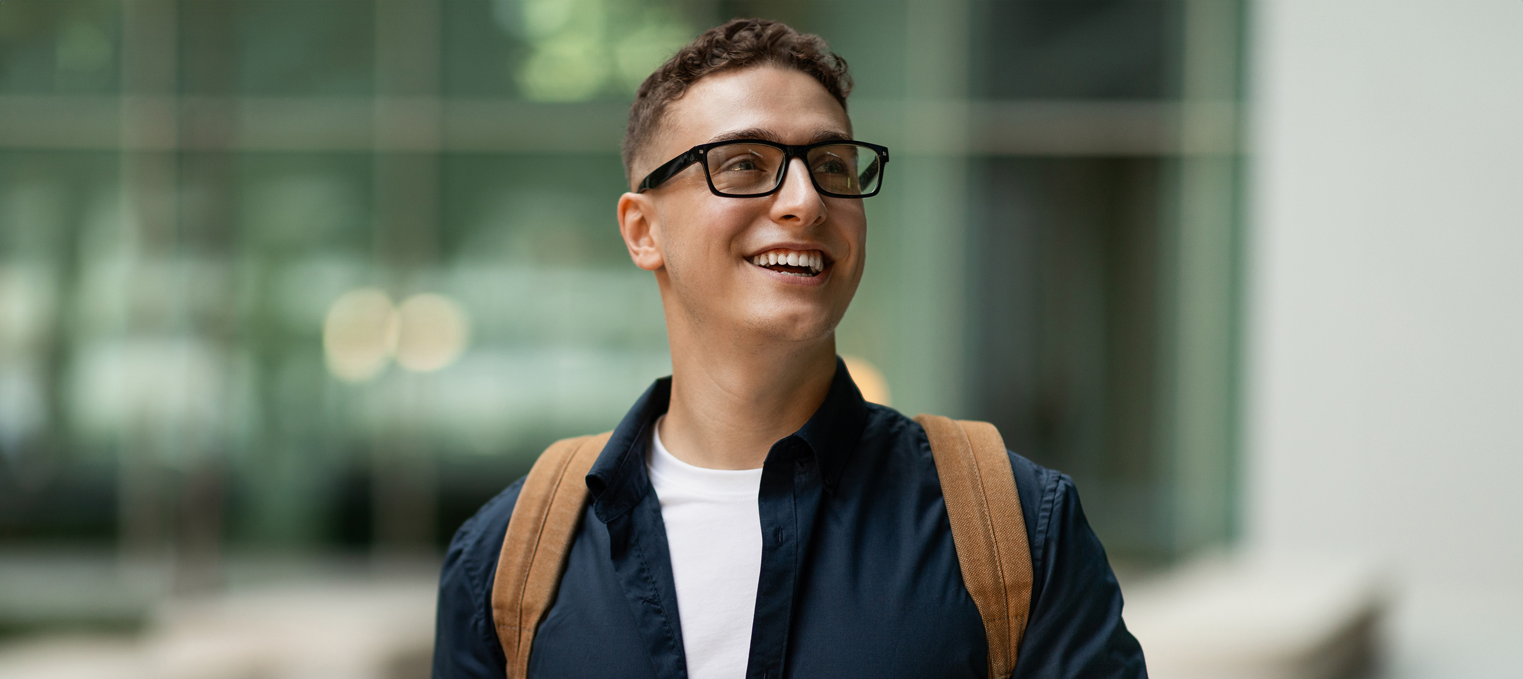 Smiling man with glasses and backpack outdoors