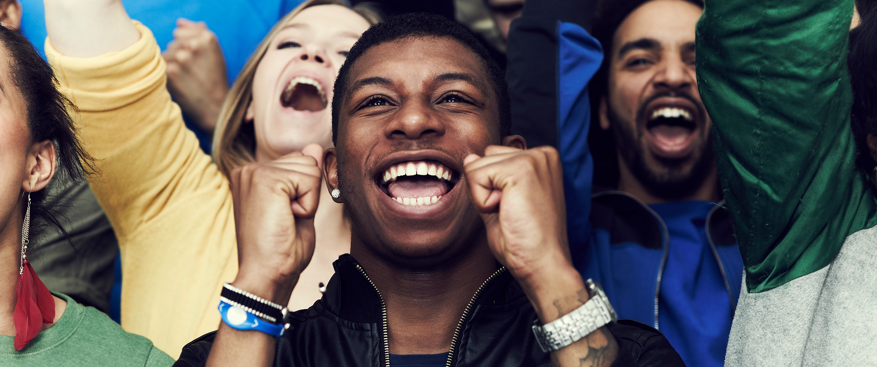 Excited group of fans cheering at a sports event with big smiles