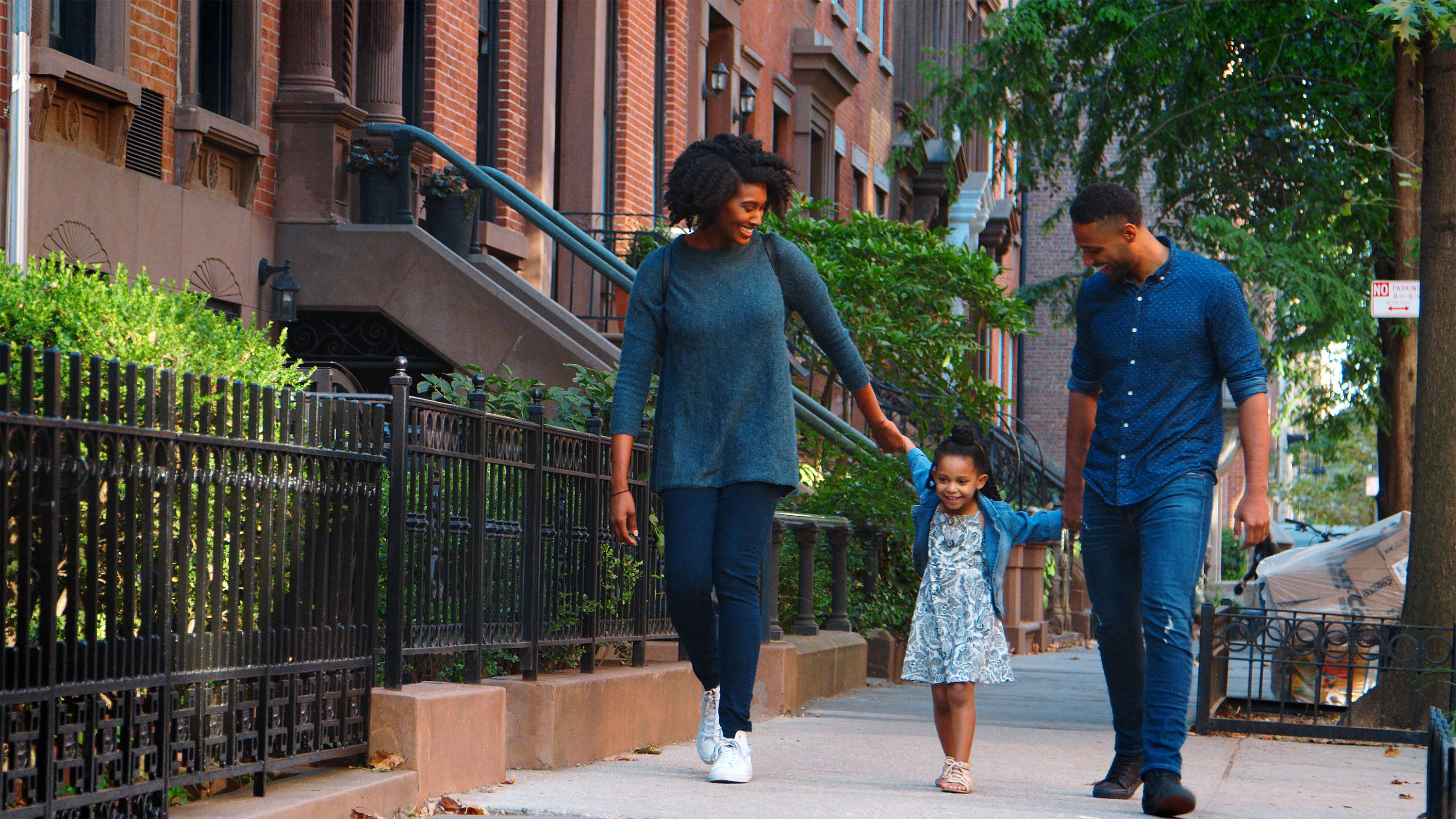 A young family walking down a city street smiling