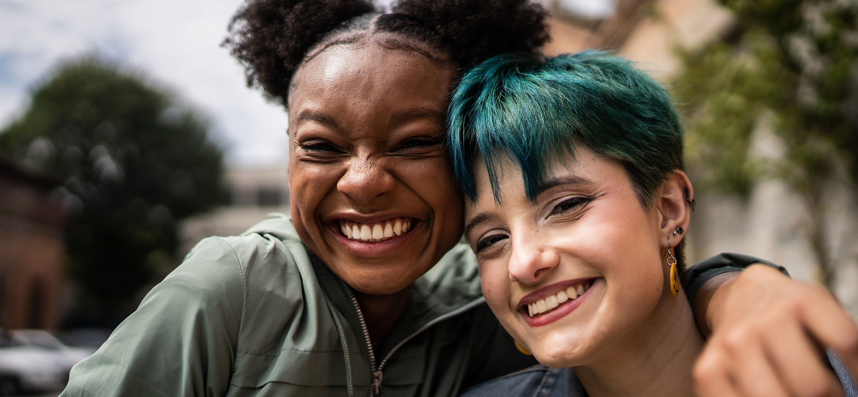 Close friends hugging and smiling joyfully outside.
