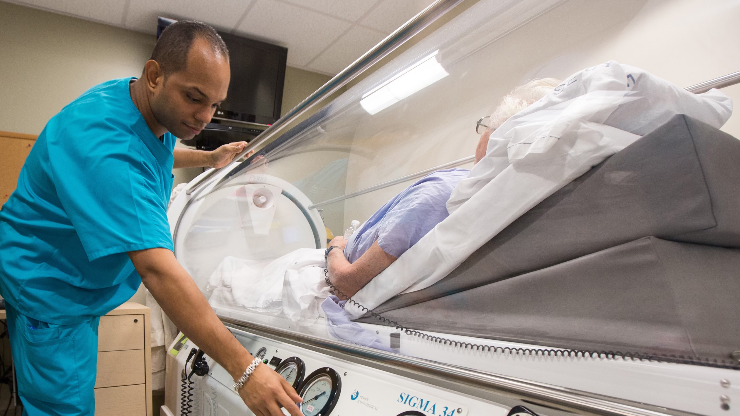 Technician tending to a woman in a hyperbaric chamber.