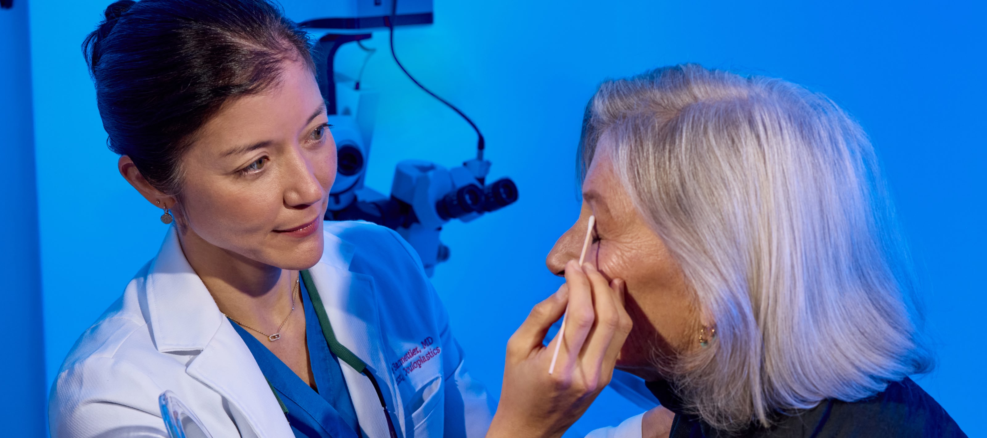 Medical technician applying ointment to a patient's eye lid with a cotton swab