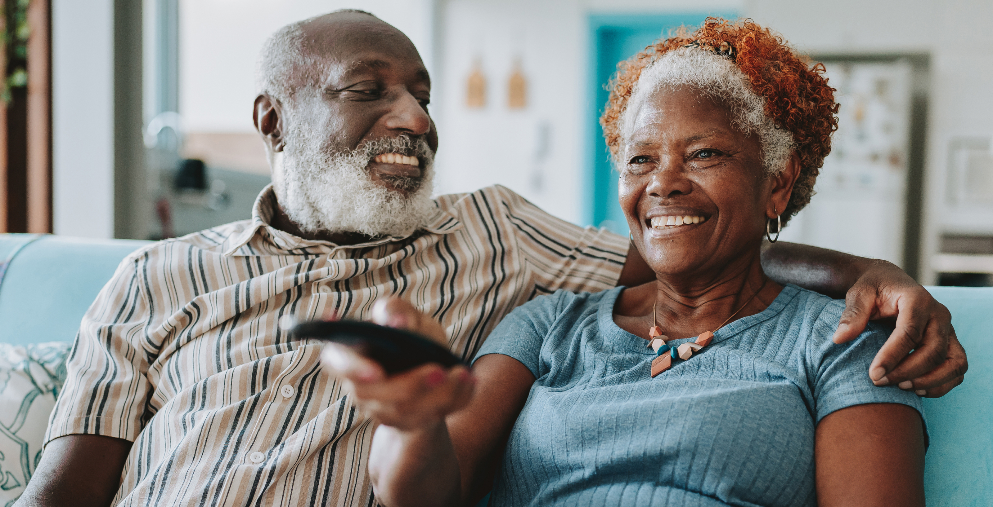 A man and woman smiling and sitting on a couch