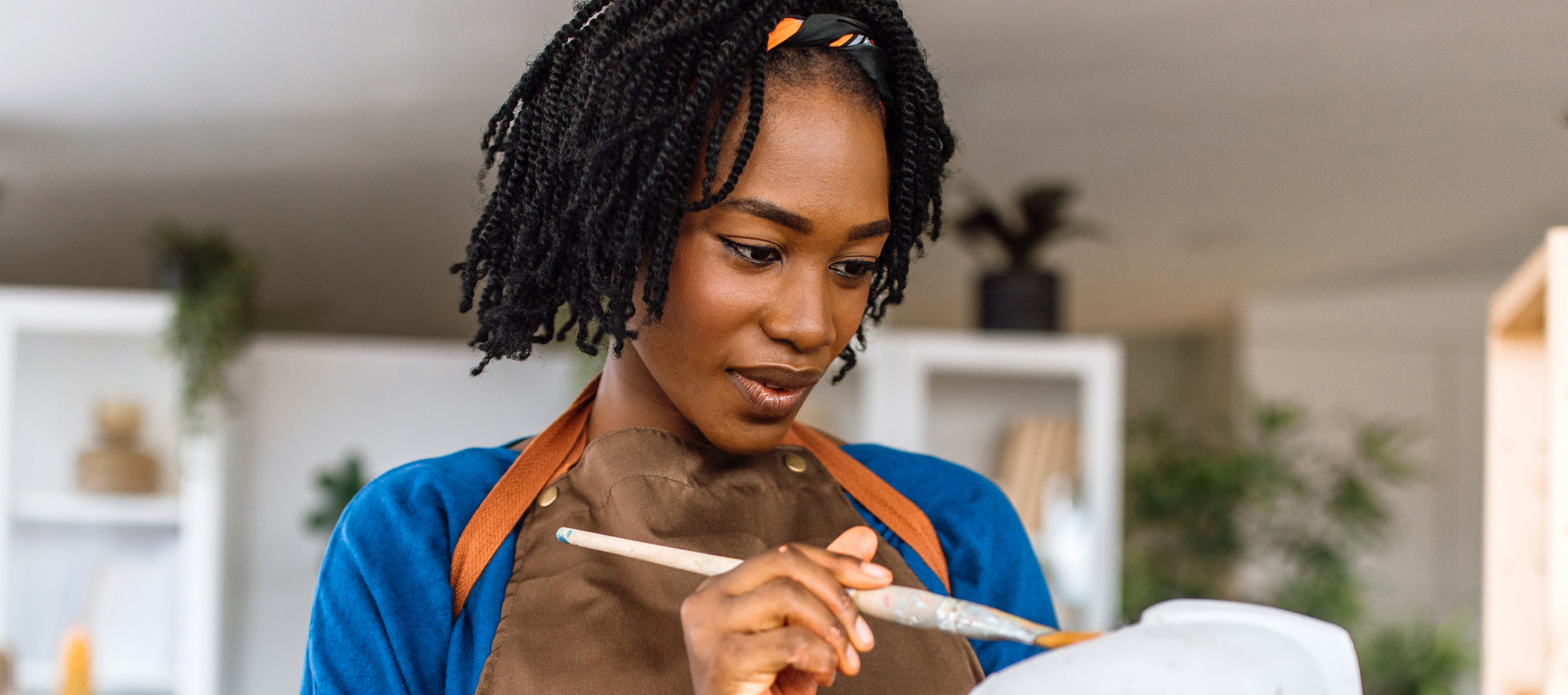 Woman holding a paint brush and appearing to paint