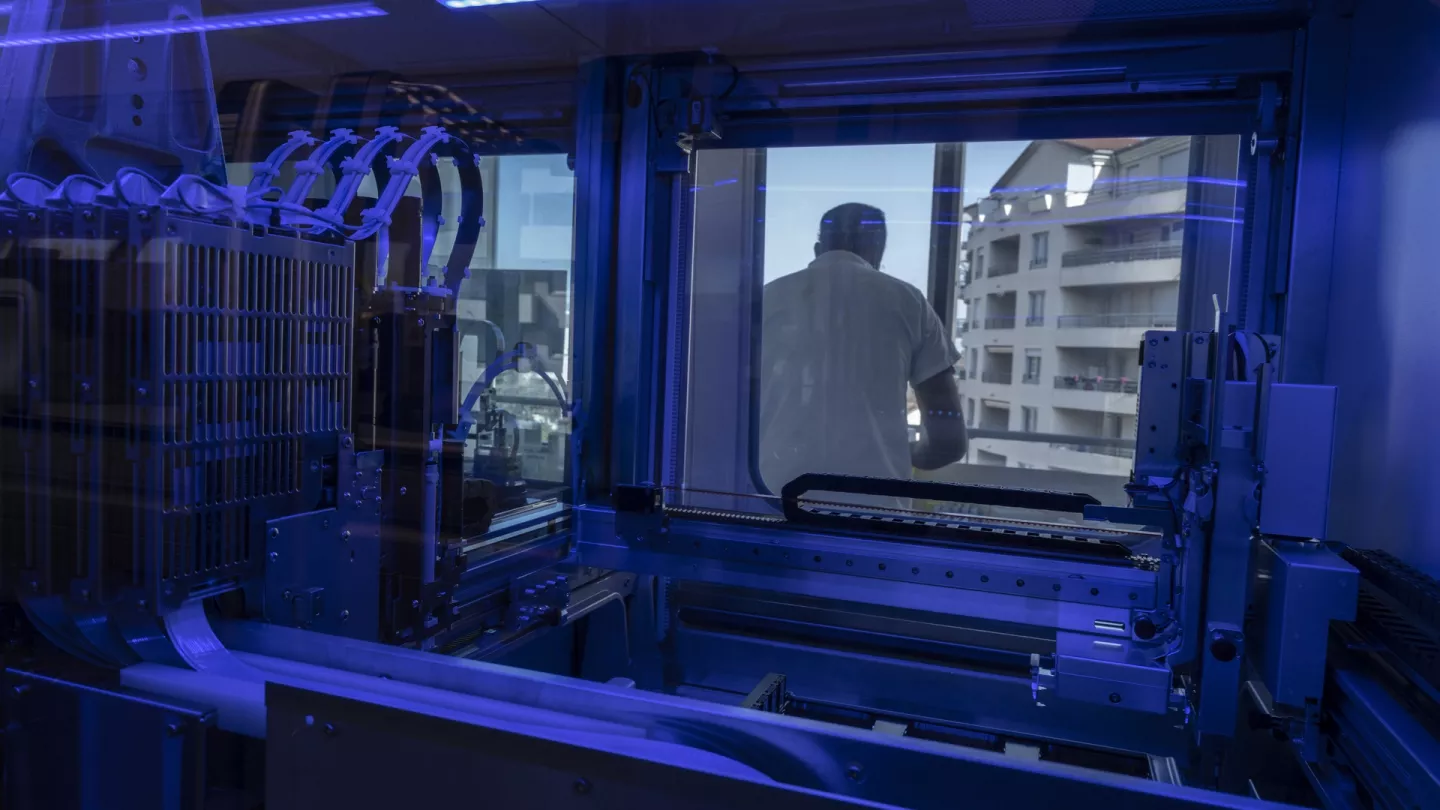 A lab technician at work, seen through the automated PCR system instrument. Credits: WHO / NOOR / Olga Kravets 