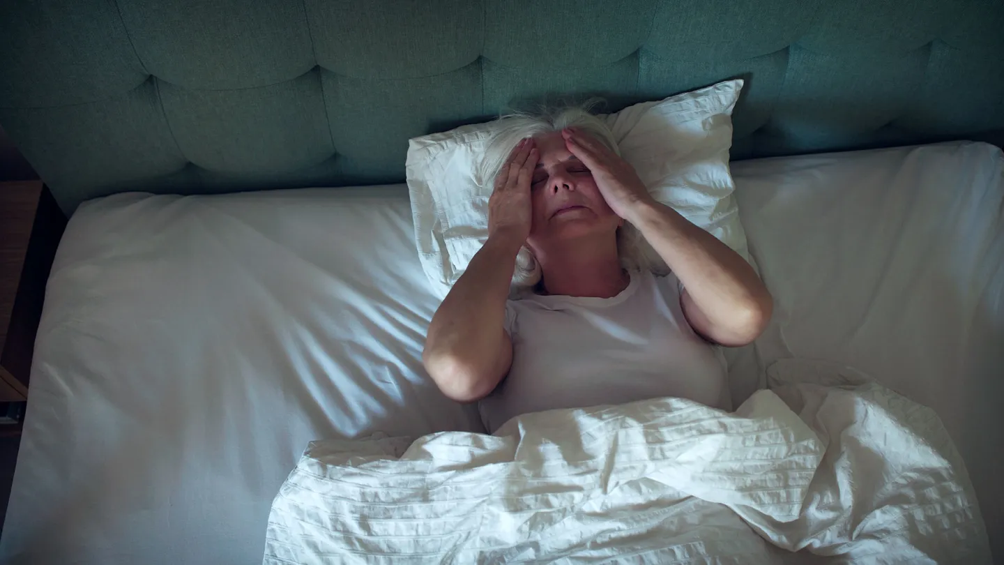 Anxious, mature woman trying to sleep at night. Dealing with sleeping disorder, head in hands