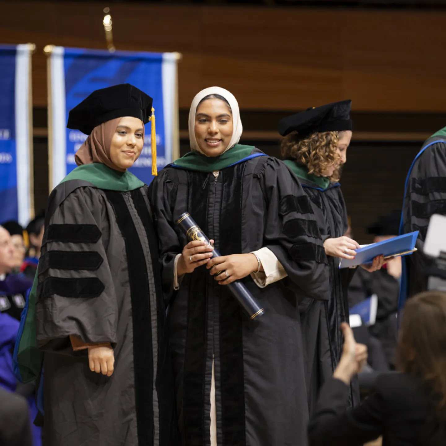 students posing on stage at graduation