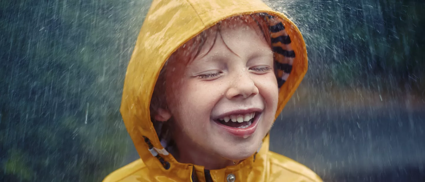 Happy smiling little boy out in the rain