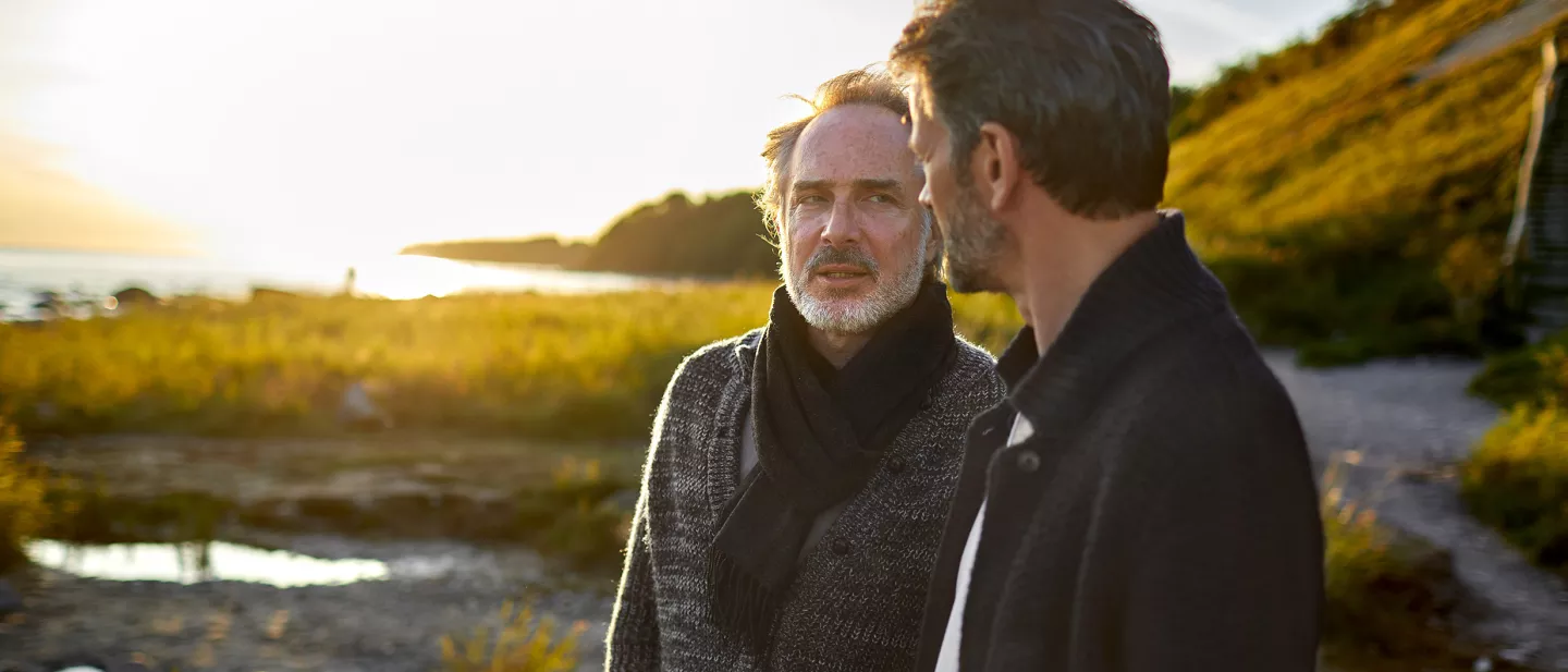 Two men talking to each other outside on a beach