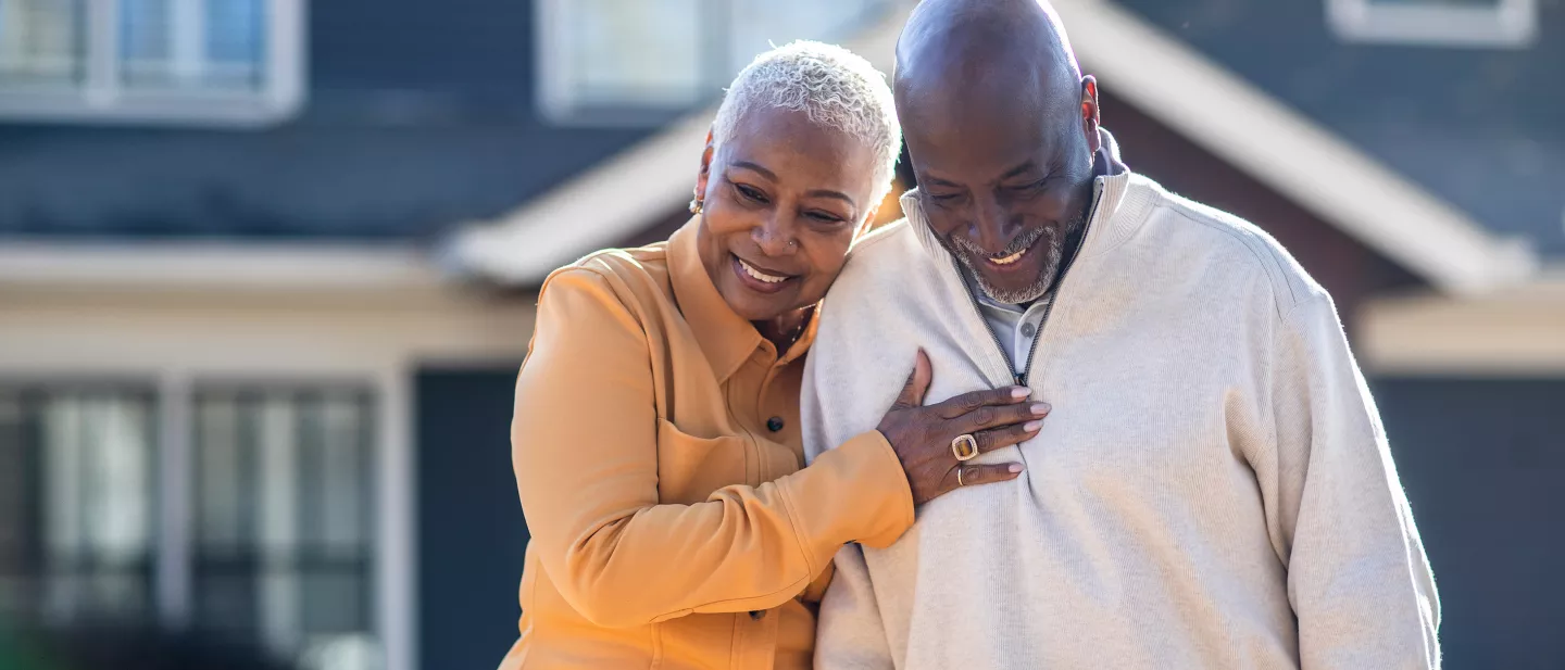Senior couple walking in front of their home.