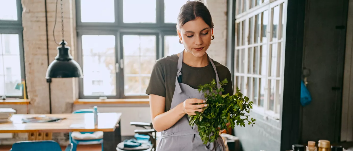 Woman holding fresh produce in sunlit, windowed room