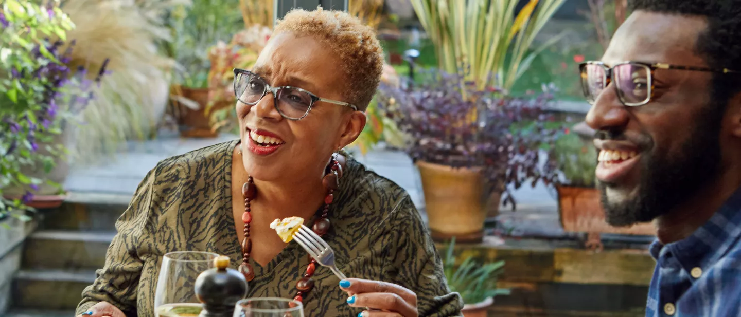 Woman and man laughing while dining together outdoors
