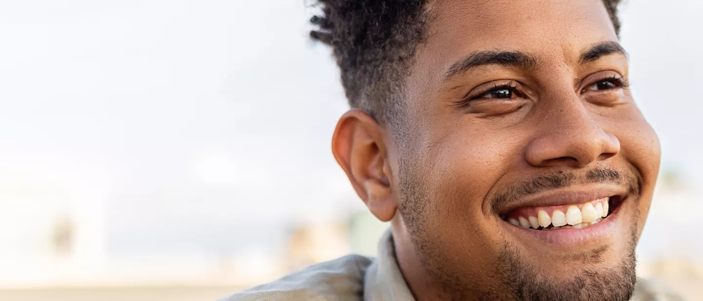 Smiling man looking into the distance with soft sunlight on his face.