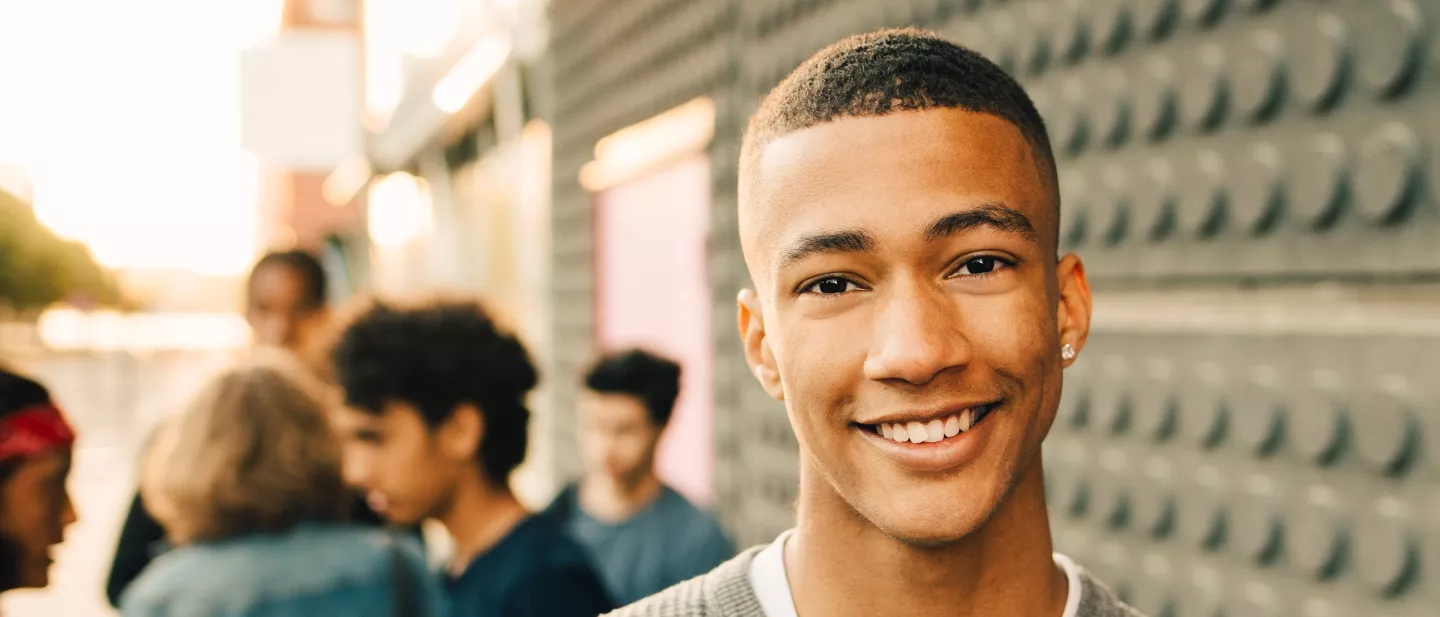 Teen boy smiling confidently with a group of friends in the background
