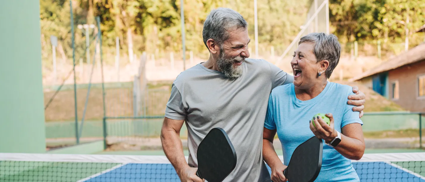 Elderly couple smiling and walking together after a game of pickleball