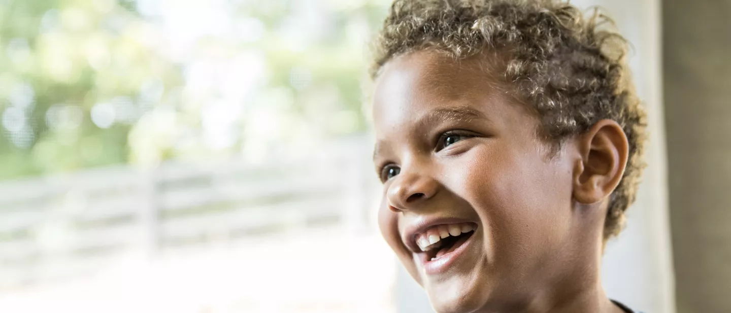 Young boy smiling brightly with window light in background