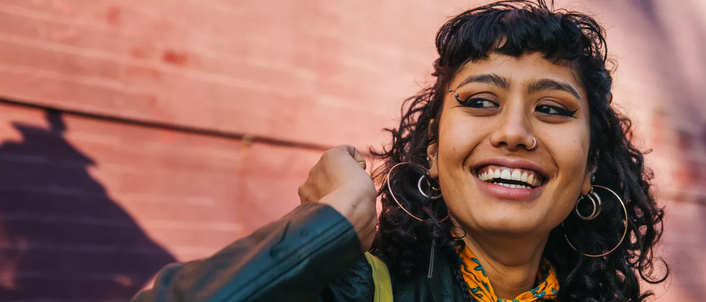 Person smiling confidently in front of a red brick wall.
