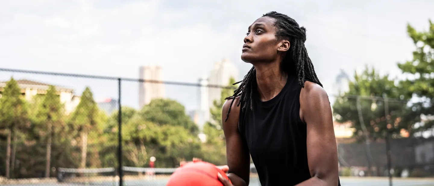 Focused woman holding basketball on outdoor court.