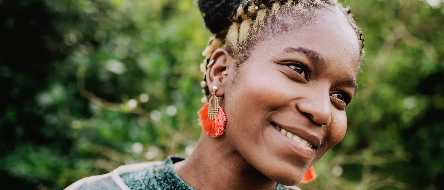 Smiling woman wearing red earrings and a green top outside