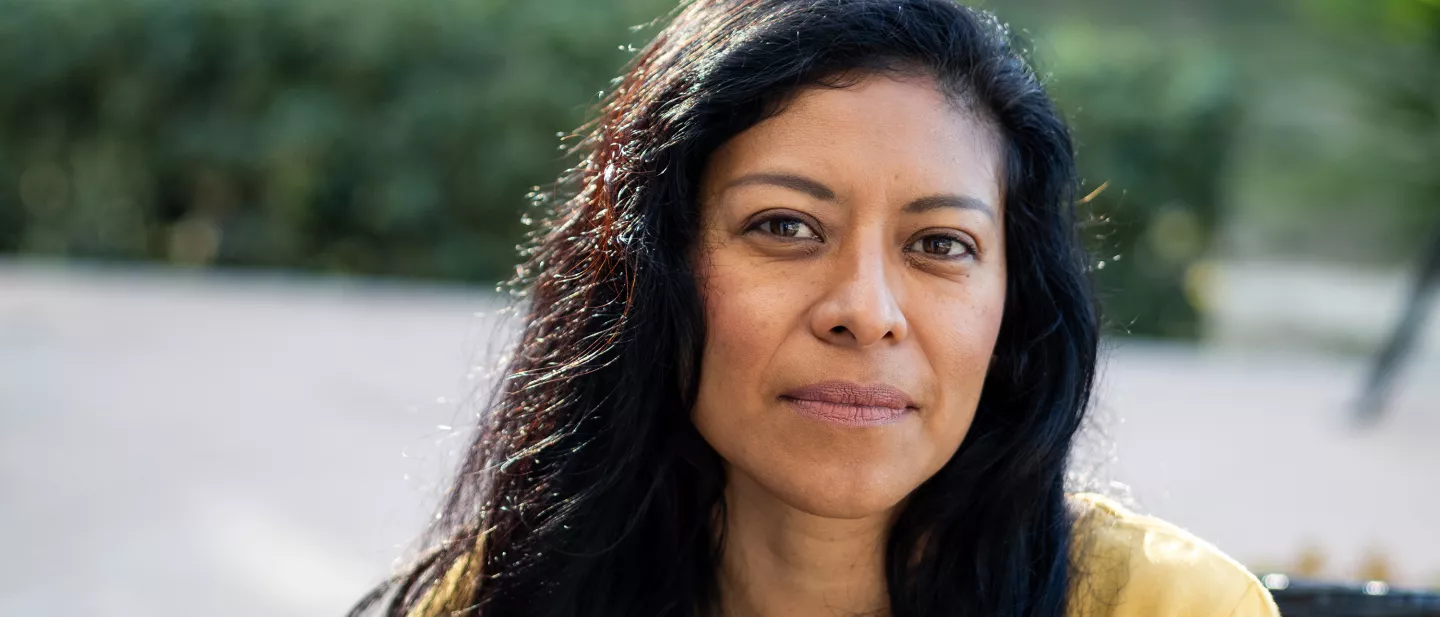 Woman with long black hair looking calmly at the camera while sitting outdoors