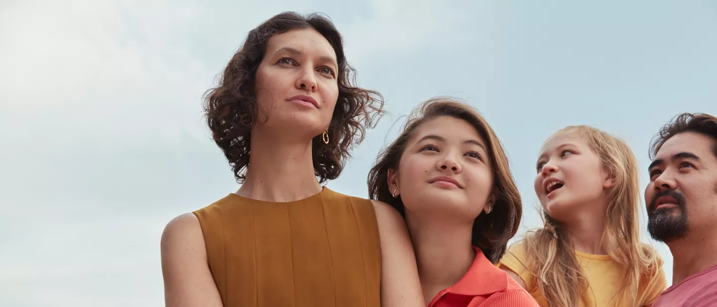 Family looking upward together under a blue sky
