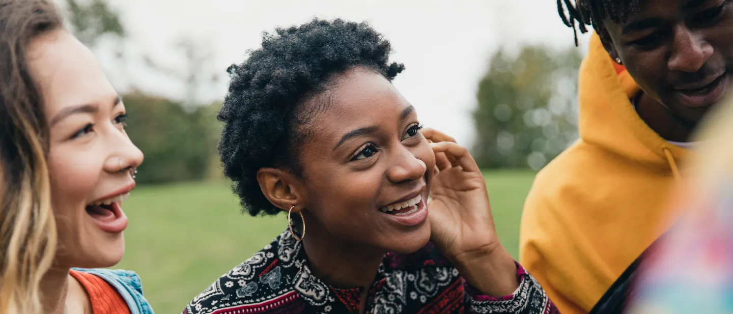 Group of friends sharing a laugh outdoors in a park.