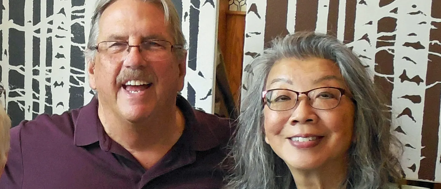 Smiling couple seated together in front of a patterned background