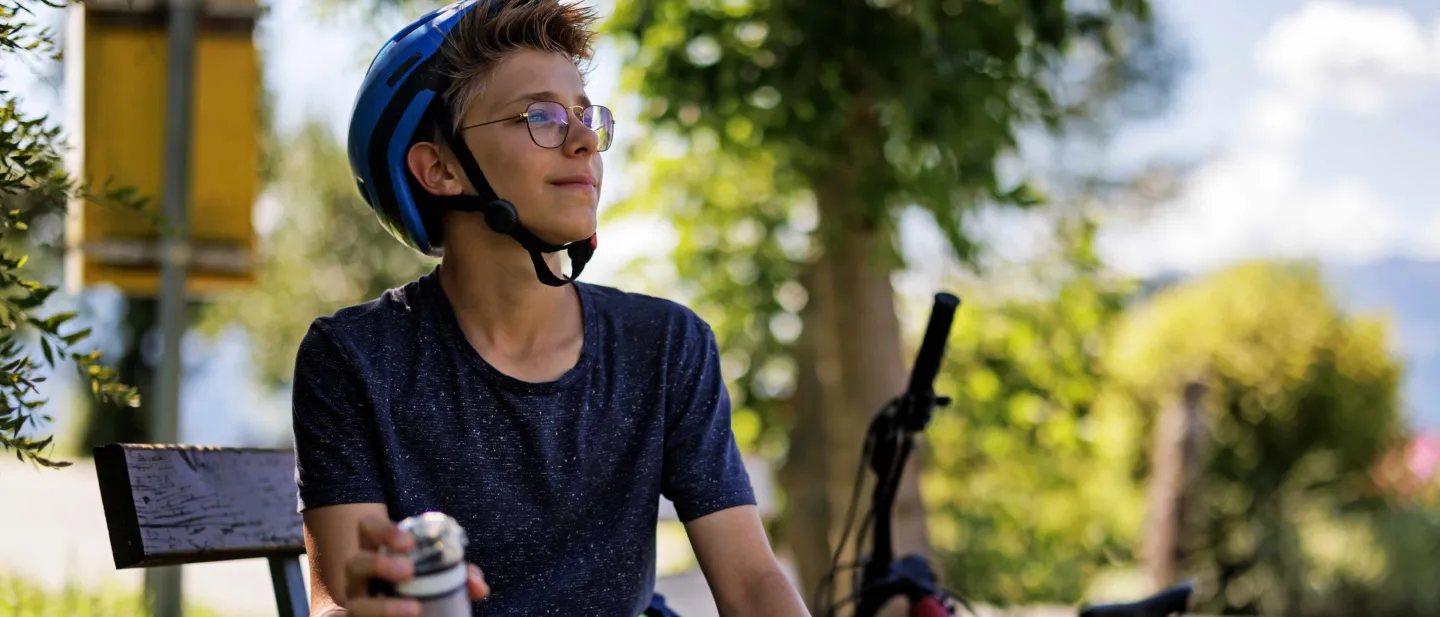 Boy on bicycle wearing eye-glasses looking far away