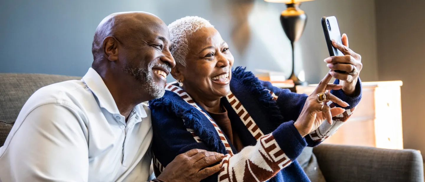 Two people sitting on a couch and looking at a mobile phone