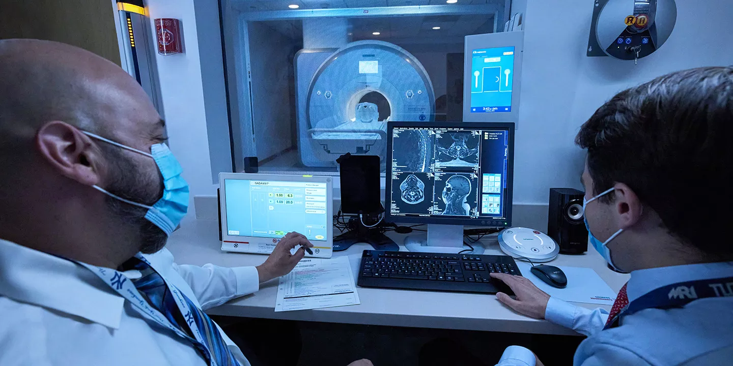 Two doctors discuss results on a computer screen in front of them.
