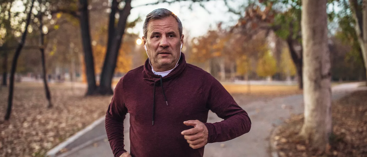 Adult male wearing headphones jogging in park