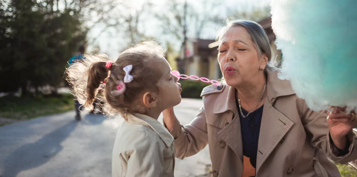 A grandmother blowing bubbles with her granddaughter.