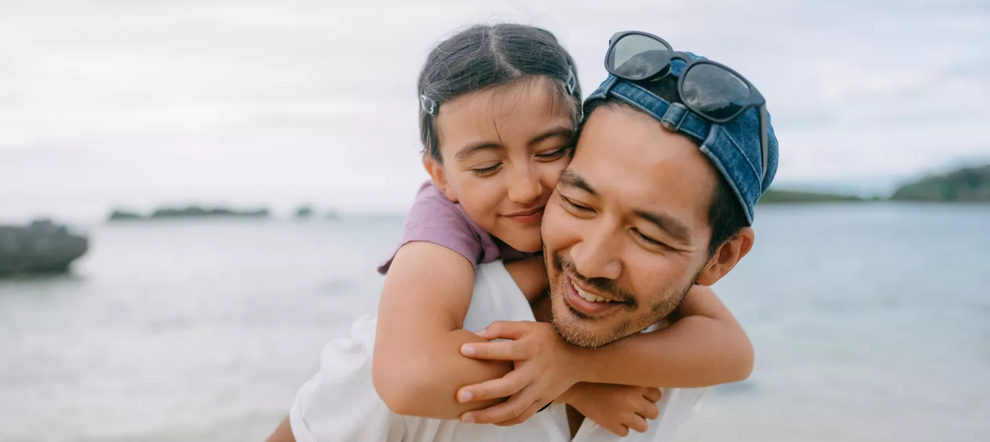 Father giving piggyback ride to young daughter on beach