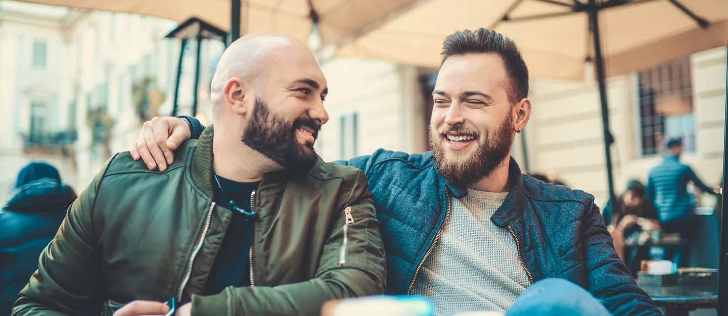 Two Smiling Friends Drinking Coffee and Talking in Coffee Shop