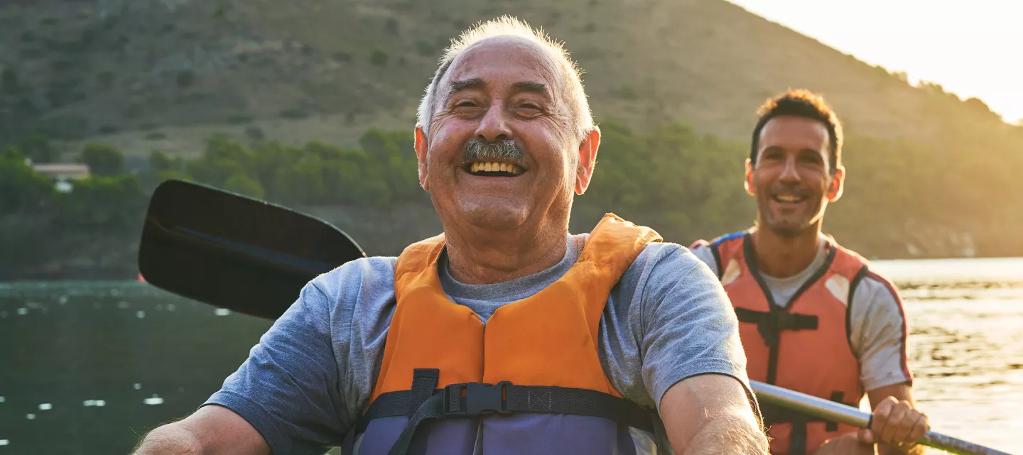 Smiling father and son kayaking on river. 