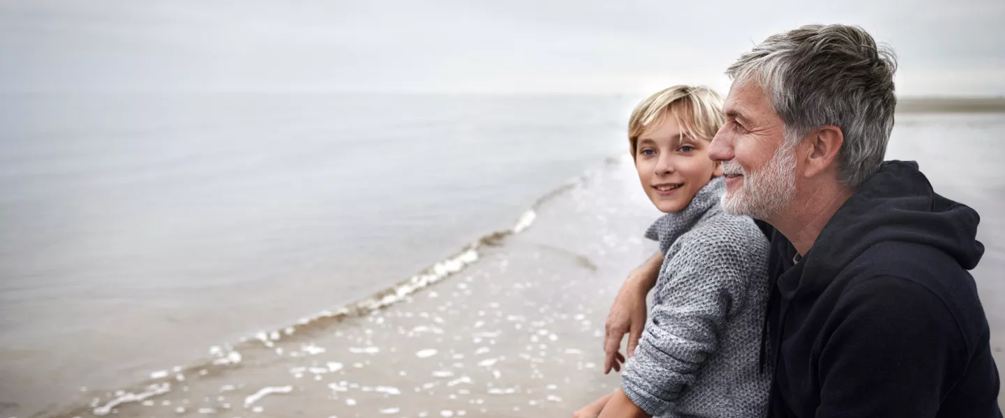 Smiling father and son at the beach on a cloudy day