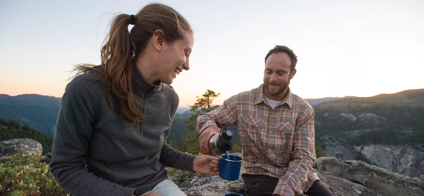 A couple enjoying tea atop a mountain.