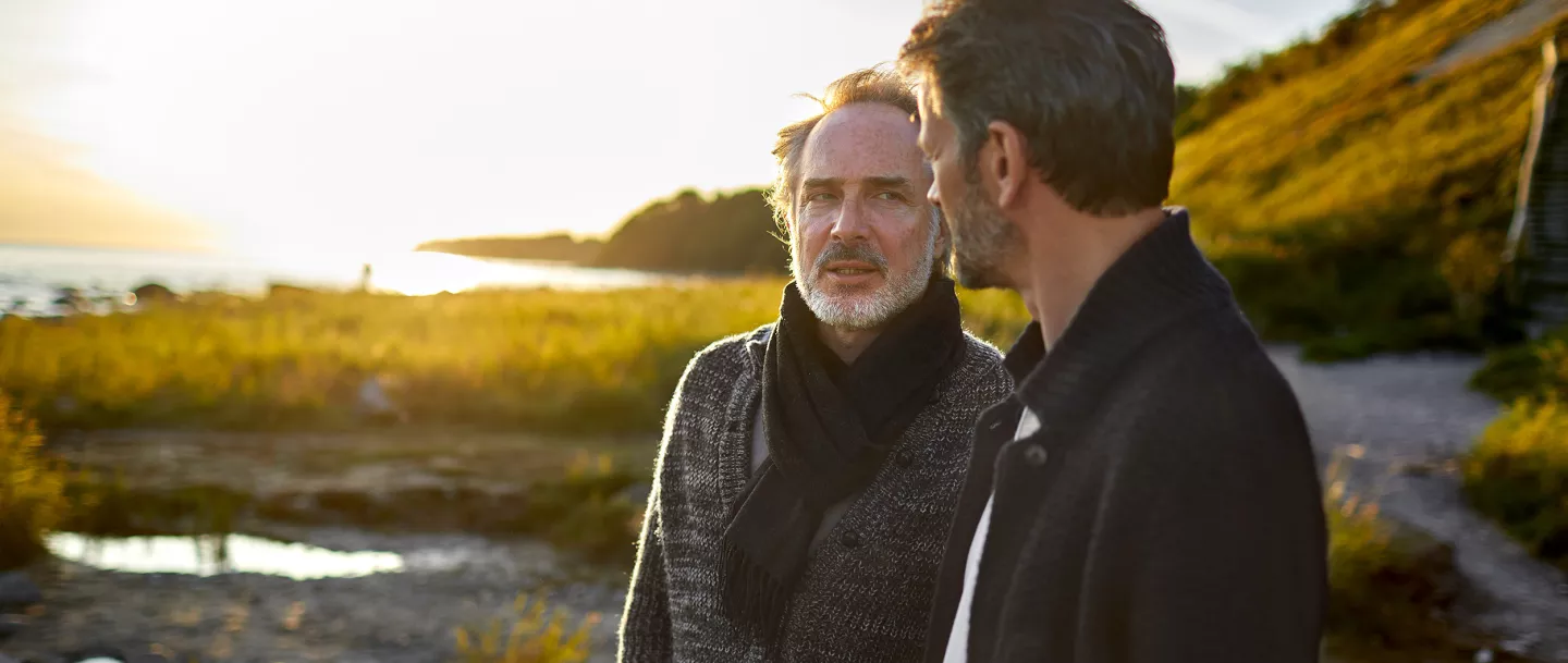 Two men talking to each other outside on a beach