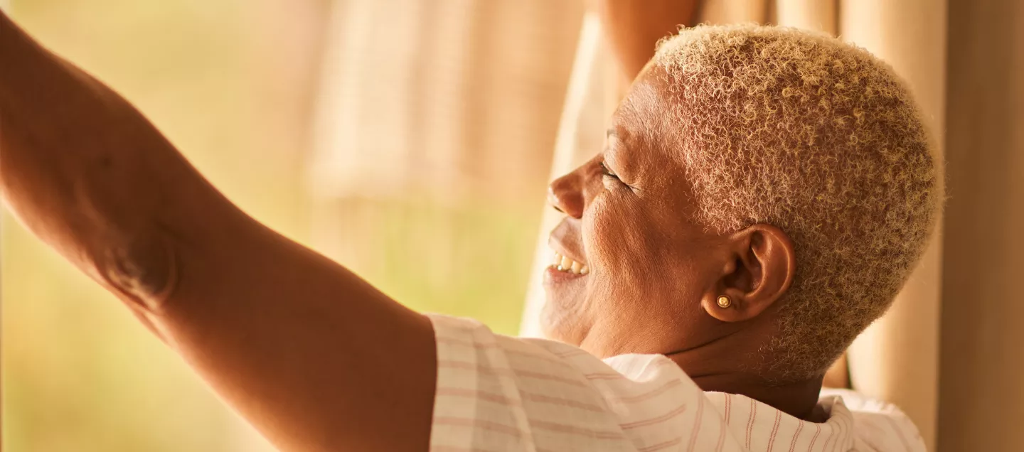Woman opening up curtains on a sunny morning