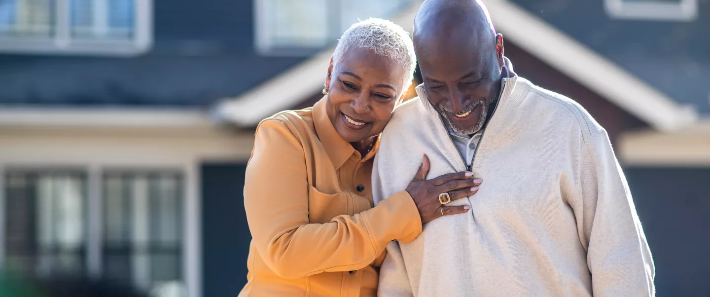 Senior couple walking in front of their home.