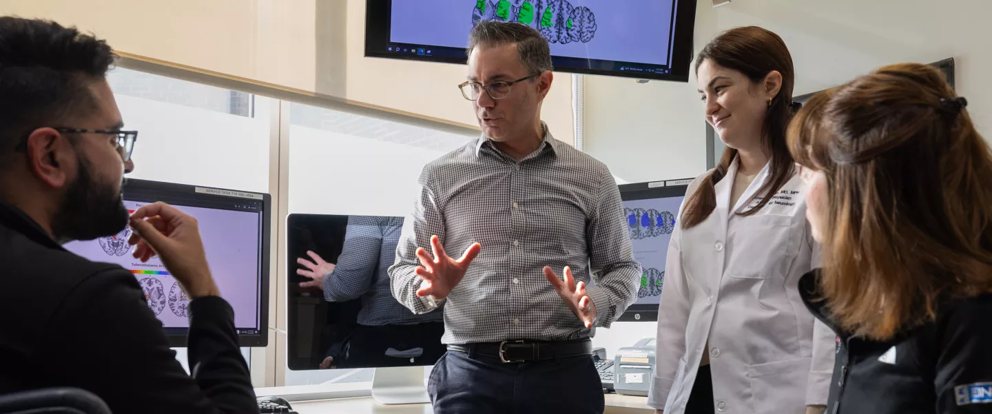 A group of physicians and fellows talking in a hospital room