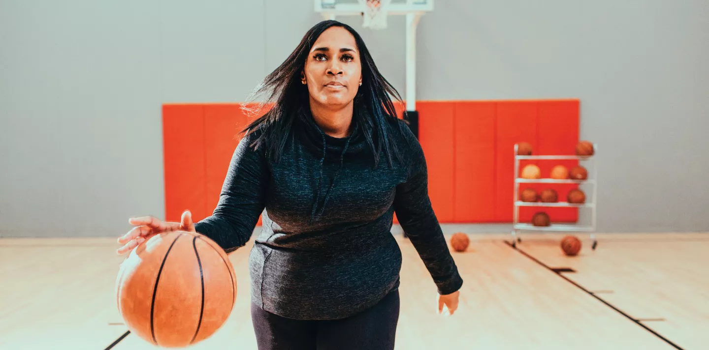 A woman dribbling a basketball in a gym