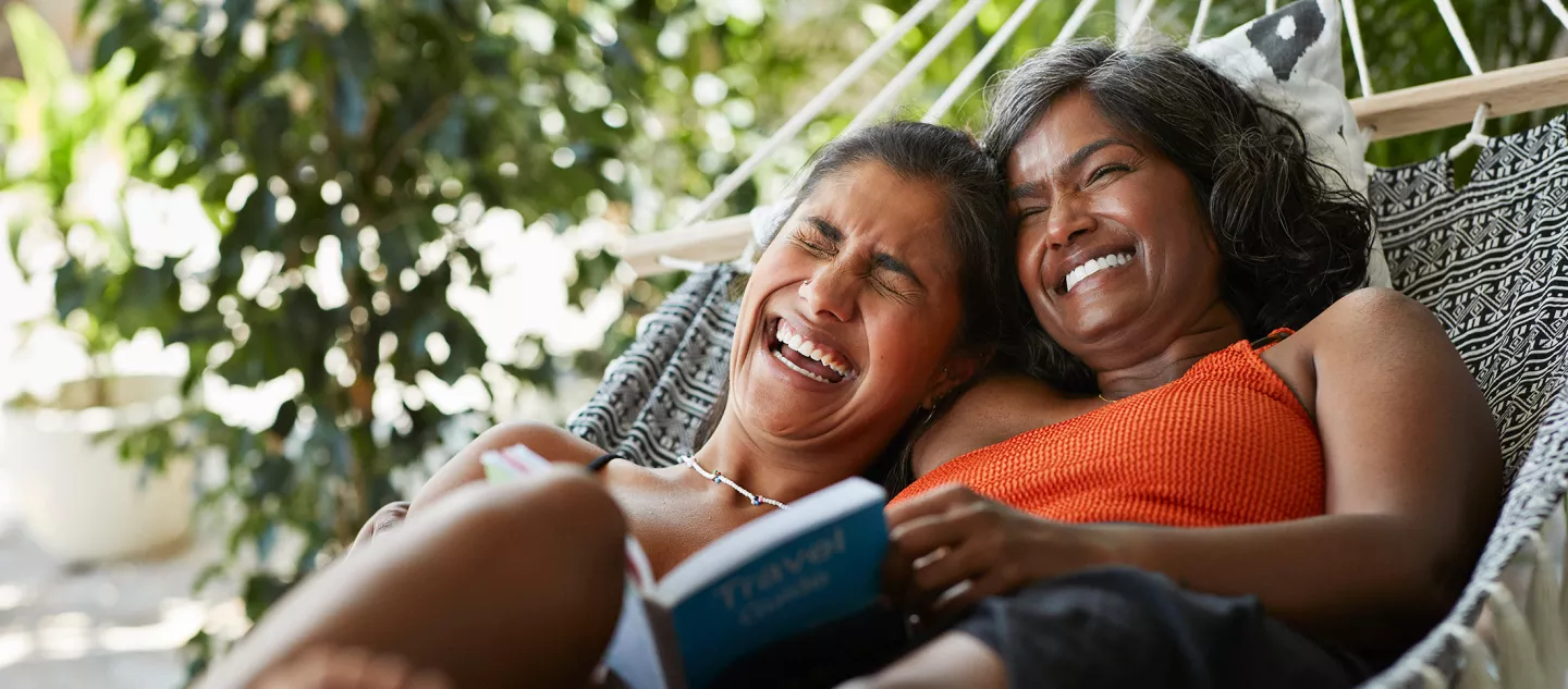 Two women reading a book in a hammock 